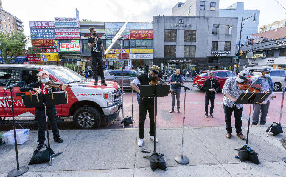 De izquierda a derecha, los miembros del NY Phil Bandwagon, la violinista Fiona Simon; el contratenor y productor Anthony Roth Costanzo; el violinista Curtis Stewart y el músico de viola Robert Rinehart actúan en el barrio Flushing de Queens, Nueva York, el viernes 2 de octubre de 2020. El equipo hizo tres conciertos no anunciados en rincones de la ciudad de Nueva York entre el viernes y el domingo, ofreciendo música de cámara dentro de las actividades de otoño de la orquesta. (AP Foto/Mary Altaffer)