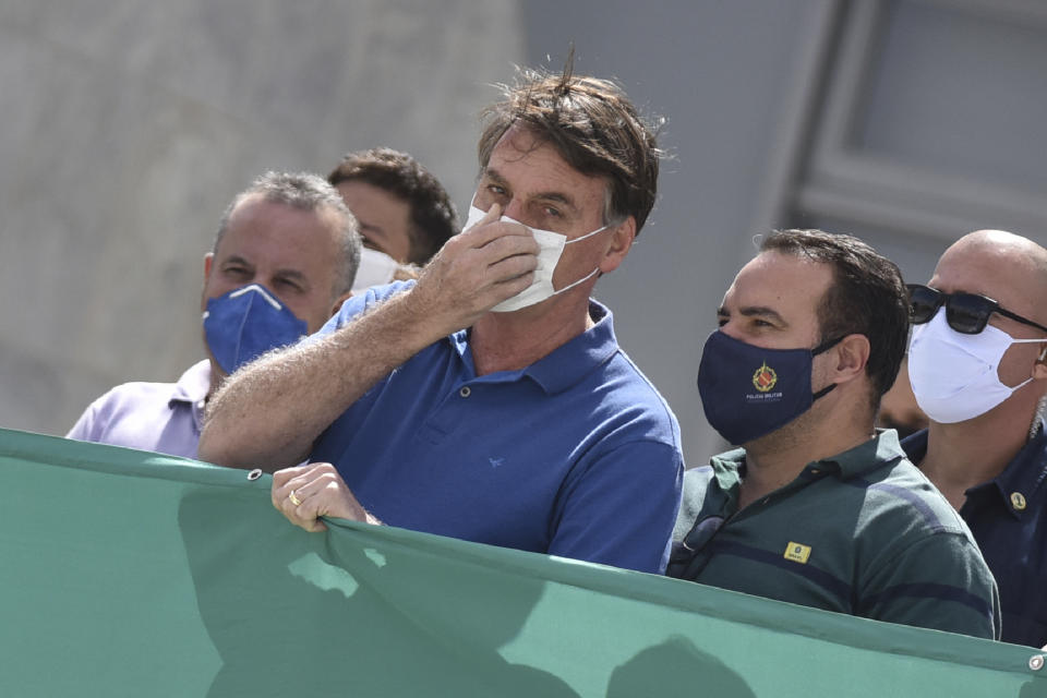 FILE - In this May 17, 2020 file photo, Brazil's President Jair Bolsonaro, wearing a protective face mask as a precaution against the spread of the new coronavirus, joins in a protest against the Supreme Court and Brazil's National Congress, in Brasilia, Brazil. A profanity-laced video showing Bolsonaro expressing frustration at his inability to get information from police and vowing to change Cabinet ministers if needed to protect his family was released Friday, May 22, 2020, at the order of a Supreme Court justice in a new blow to a president whose popularity has been sagging. (AP Photo/Andre Borges, File)