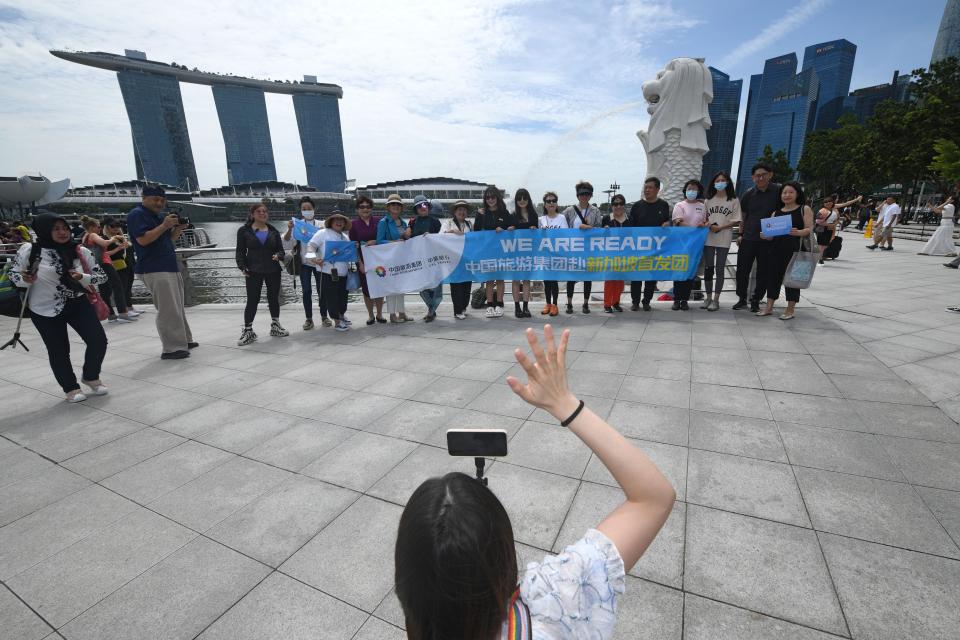 Chinese tourists pose for a group photo at Merlion Park in Singapore on Feb. 7, 2023. Singapore welcomed the first batch of Chinese tour group since China resumed outbound group tours. (Photo by Then Chih Wey/Xinhua via Getty Images)