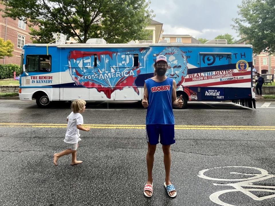 Kyle Kemper stands next to a child  in front of an RV.