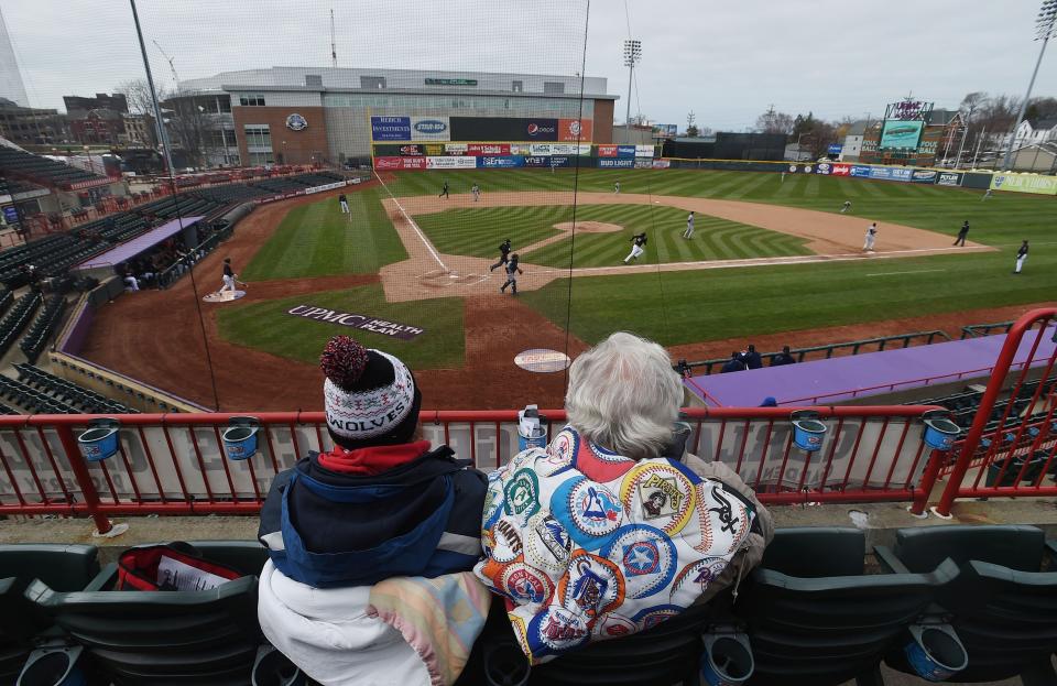FILE - In this April 18, 2018, file photo, Debbie McCracken, left, and Ted Grimm, both of Millcreek Township, watch the Erie SeaWolves play the Trenton Thunder in the opening game of a Double-A baseball doubleheader in Erie, Pa. Major League Baseball is pushing a proposal to whack 42 teams _ and several entire leagues _ from its vast network of minor-league affiliates that bring the game to every corner of country. (Jack Hanrahan/Erie Times-News via AP, File)