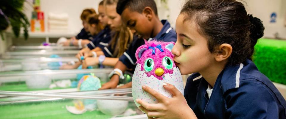 Young girl kisses her Hatchimal, other kids in the background