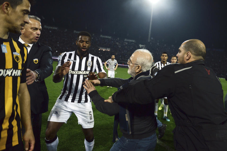 FILE - PAOK owner, businessman Ivan Savvidis, second right, approaches AEK Athens' Manager Operation Department Vassilis Dimitriadis, second left, as his bodyguard and PAOK's player Fernando Varela from Portugal, center, try to stop him during the Greek League soccer match between PAOK and AEK Athens in the northern Greek city of Thessaloniki, Sunday, March 11, 2018. A disputed goal at the end of the Greek league match led to a pitch invasion by Savvidis, who appeared to be carrying a gun. (AP Photo, File)