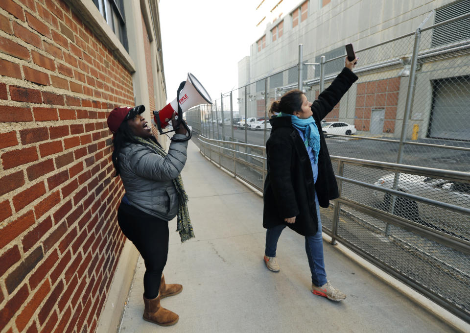 Catana Yehudah, of the Bronx, uses a megaphone to speak to prisoners from outside the Metropolitan Detention Center, a federal prison of all security levels, where prisoners haven't had access to heat, hot water, electricity and sanitary conditions since earlier in the week, including throughout the recent frigid weather, Sunday, Feb. 3, 2019, in the Brooklyn borough of New York. Activist Veronica Matus, right, joins Yehudah as they try to elicit responses from the prisoners. (AP Photo/Kathy Willens)