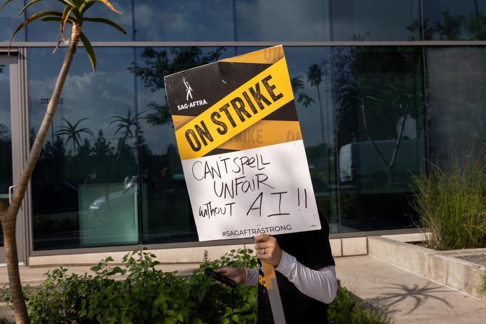 A supporters of SAG-AFTRA picket holding a sign relating to the union's AI concerns.