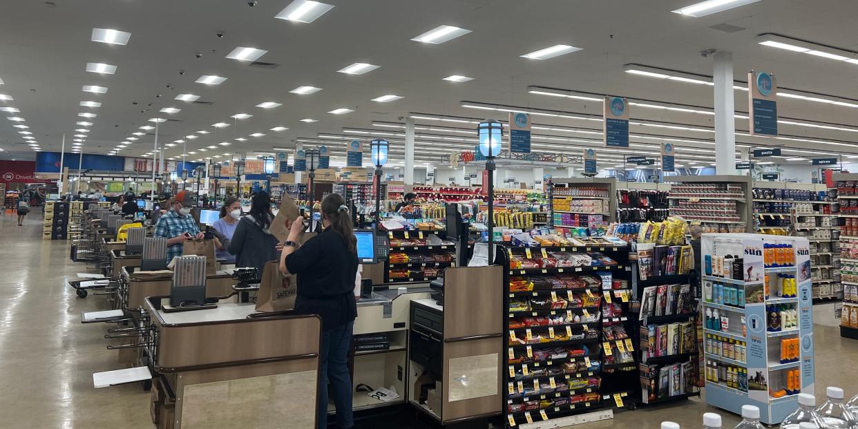 Grocery store cashiers working at the checkout aisle.