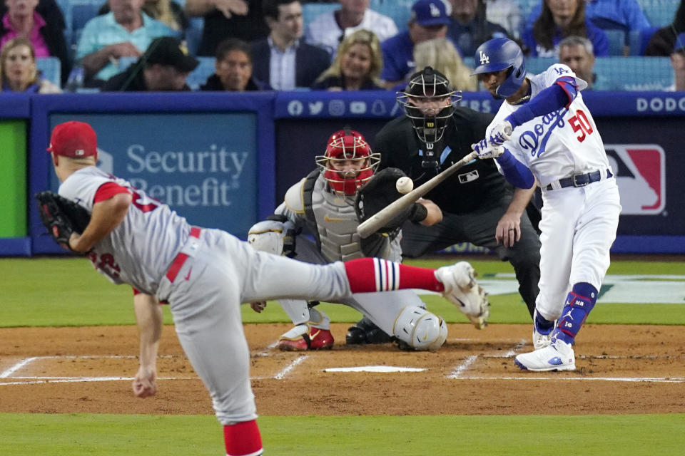 Los Angeles Dodgers' Mookie Betts, right, hits a solo home run as St. Louis Cardinals starting pitcher Jack Flaherty, left, watches along with catcher Willson Contreras, second from left and home plate umpire Nate Tomlinson during the first inning of a baseball game Friday, April 28, 2023, in Los Angeles. (AP Photo/Mark J. Terrill)
