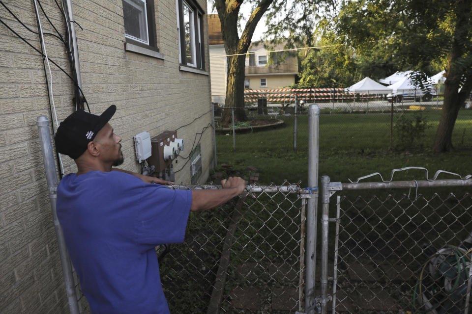 Jose Torres looks toward a neighbor's yard where a police investigation is underway following a report that two bodies may be buried there in suburban Lyons, Ill., Friday, Aug. 27, 2021. Authorities are planning to excavate the suburban Chicago backyard Friday after two adult brothers found living in what police called a “hoarder home" said they had buried the bodies of their mother and sister there. (Antonio Perez/Chicago Tribune via AP)