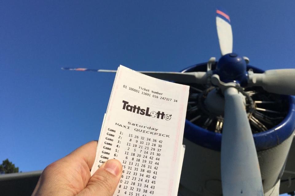 Man hold winning TattsLotto ticket in front of plane. Source: The Lott