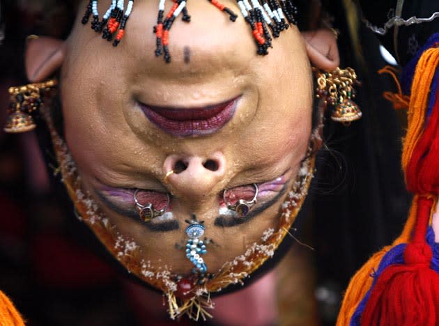 A folk dancer from the desert Indian state of Rajasthan lifts rings with her eyelids during a cultural program organised during the "Teej" festival in the northern Indian city of Chandigarh August 2, 2011. Hindu women fast and pray for the good health and long life of their husbands during the Teej festival as Teej falls in the Hindu month of Shravan (July-August) and welcomes the advent of the monsoon. REUTERS/Ajay Verma