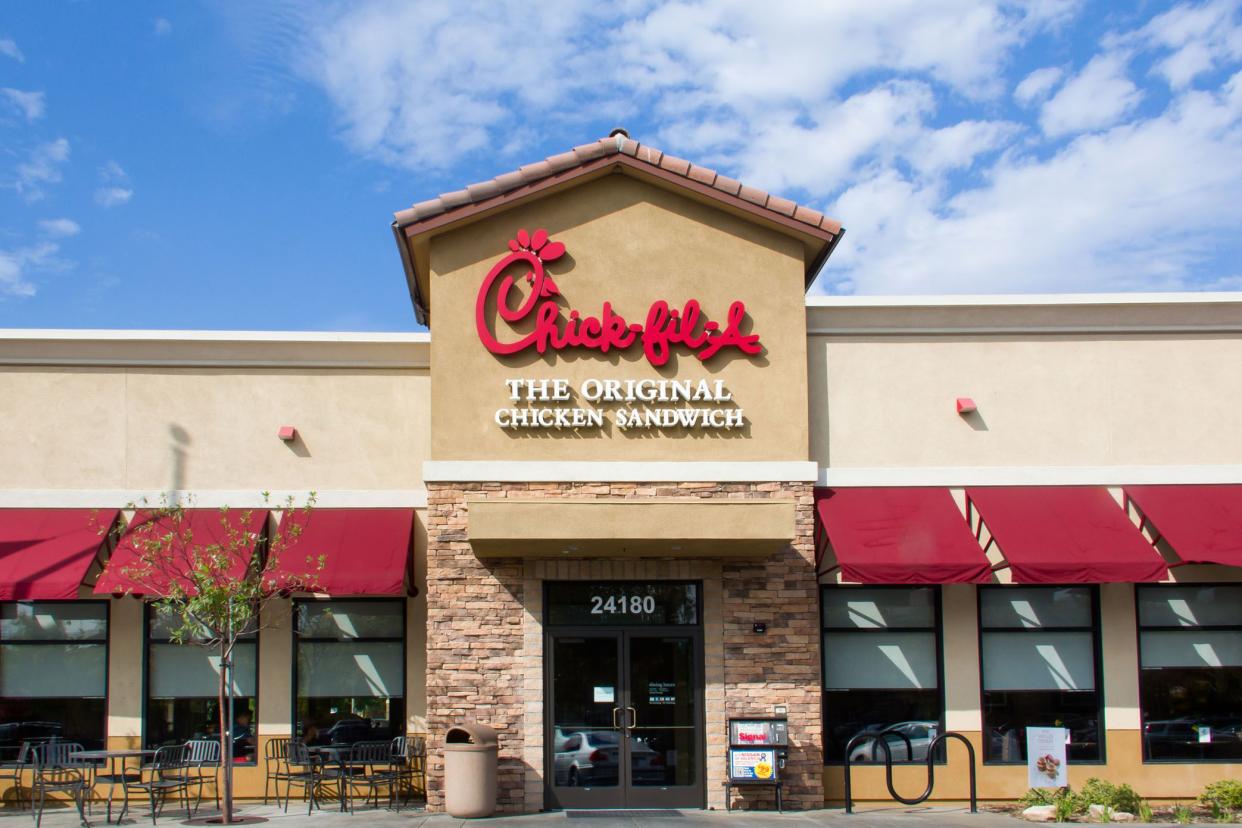 Front exterior of a Chick-fil-A restaurant in Santa Clarita, California with outdoor seating area against a blue sky with white clouds