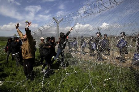 Protesting migrants try to bring down part of a border fence as Macedonian police stand guard during clashes at a makeshift camp for refugees and migrants at the Greek-Macedonian border near the village of Idomeni, Greece, April 10, 2016. REUTERS/Alexandros Avramidis