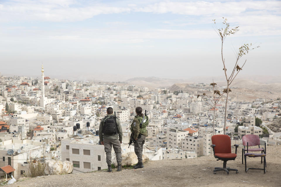 FILE - In this Dec. 10, 2017 file photo, Israeli border police officers look over the Arab neighborhood of Issawiyah in Jerusalem. A dispute over Israeli restrictions on Palestinian voters in east Jerusalem is threatening to cancel or delay the first Palestinian elections in more than 15 years. (AP Photo/Oded Balilty, File)