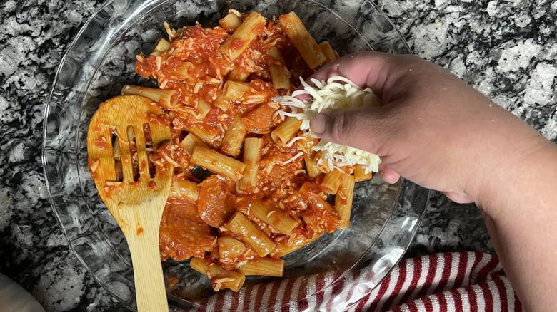 hand putting cheese on pasta