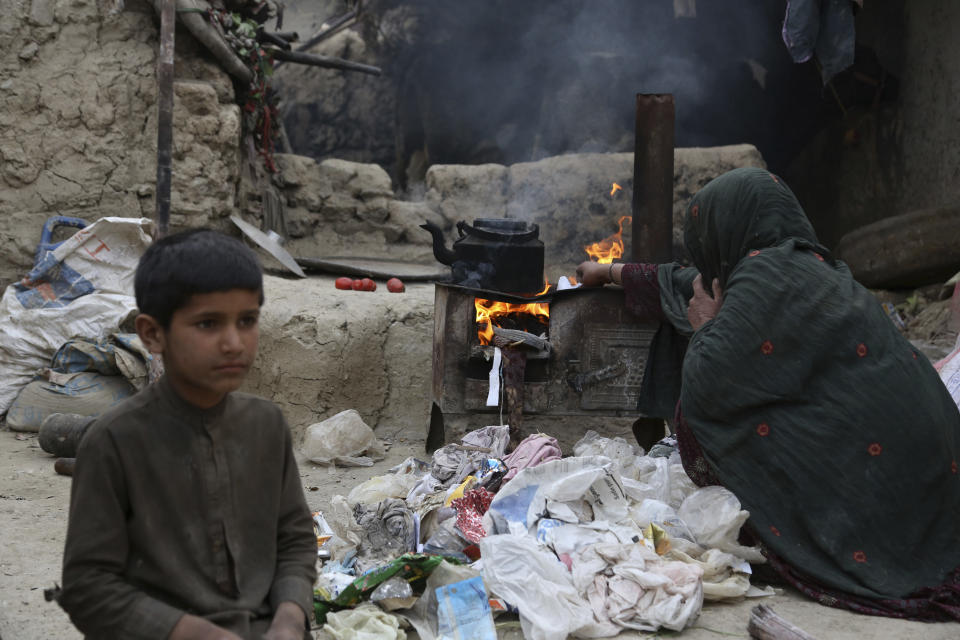 In this Oct. 29, 2019 photo, a woman who fled with her husband Yousuf and family from their home in eastern Afghanistan, burns plastic to make tea at a camp for displaced people, in Kabul, Afghanistan. The pollution may be even deadlier than Afghanistan’s war, now 18 years long. There are no official statistics on how many Afghans die of pollution-related illnesses, but the research group State of Global Air said more than 26,000 deaths could be attributed to it in 2017. (AP Photo/Rahmat Gul)