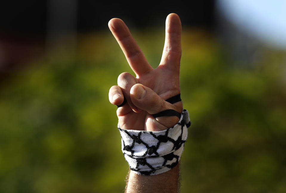 A protester flashes a victory sign with a representation of a Palestinian headscarf on his hand, during a protest in support of Palestinians in the latest round of violence between Palestinians and Israelis, in Beirut, Lebanon, Tuesday, May 11, 2021. A confrontation between Israel and Hamas sparked by weeks of tensions in contested Jerusalem escalated Tuesday. (AP Photo/Hussein Malla)