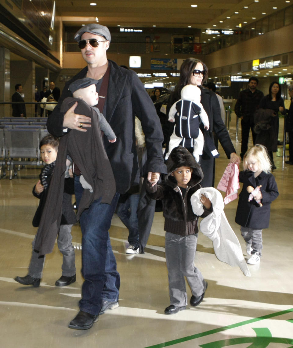 U.S. actors Brad Pitt and Angelina Jolie arrive with their children at Narita airport, near Tokyo, January 27, 2009. Pitt is in Japan to promote the film "The Curious Case of Benjamin Button". From L-R: Pax, Knox Leon (carried by Pitt), Maddox (obscured), Zahara, Vivienne Marcheline (carried by Jolie) and Shiloh. REUTERS/Toru Hanai (JAPAN)