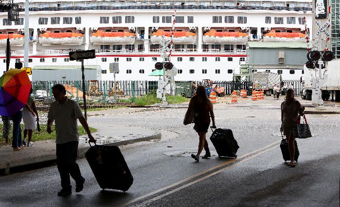 Passengers disembark from the Carnival Conquest after the cruise ship arrived at the Alabama Cruise Terminal on the Mobile River on Sunday, July 7, 2013, in downtown Mobile, Ala. The Conquest was diverted from New Orleans to Mobile after a tugboat sank in the Mississippi River Saturday, closing the river. (AP Photo/AL.com, Mike Brantley)