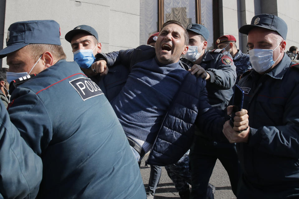 Police detain a man during a protest against an agreement to halt fighting over the Nagorno-Karabakh region, in Freedom Square in Yerevan, Armenia, Wednesday, Nov. 11, 2020. Thousands of people flooded the streets of Yerevan once again on Wednesday, protesting an agreement between Armenia and Azerbaijan to halt the fighting over Nagorno-Karabakh, which calls for deployment of nearly 2,000 Russian peacekeepers and territorial concessions. Protesters clashed with police, and scores have been detained. (AP Photo/Dmitri Lovetsky)