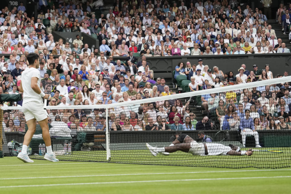 Francis Tiafoe of the United States lays on the court during his third round match against Spain's Carlos Alcaraz, left, at the Wimbledon tennis championships in London, Friday, July 5, 2024. (AP Photo/Alberto Pezzali)