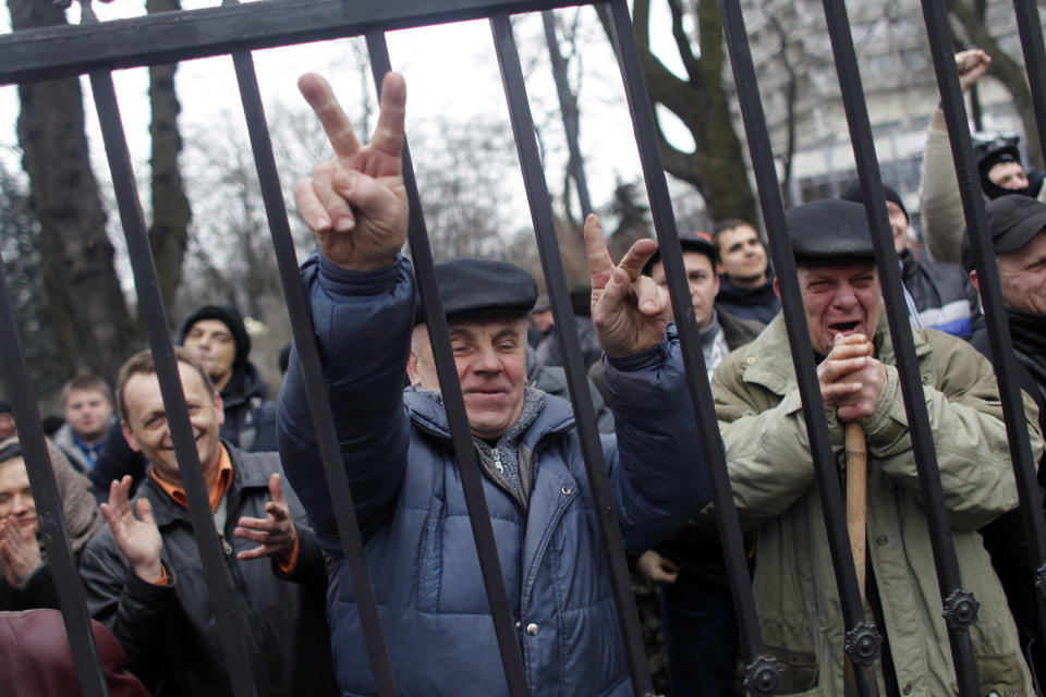 Anti-government protesters react to news from Ukraine's parliament in Kiev, Ukraine, Saturday, Feb. 22, 2014. Protesters took control of Ukraine's capital on Saturday, seizing the president's office as parliament sought to oust him and form a new government. (AP Photo/ Marko Drobnjakovic)