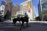 Chicago mounted police officers patrol Chicago's Magnificent Mile with an Andy Warhol mural of Marilyn Monroe in the background, on Tuesday, Aug. 11, 2019. (AP Photo/Charles Rex Arbogast)