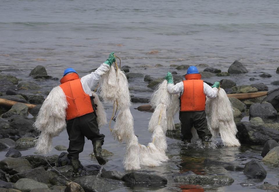 Workers carry a type of skimmer that collects oil waste during a clean-up campaign on Pocitos Beach in Ancon, Peru, Tuesday, Feb. 15, 2022. One month later, workers continue the clean-up on beaches after contamination by a Repsol oil spill. (AP Photo/Martin Mejia)