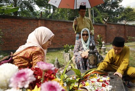 A family cleans a relative's grave on the first day of Eid al-Fitr in Kuala Lumpur July 28, 2014. REUTERS/Olivia Harris