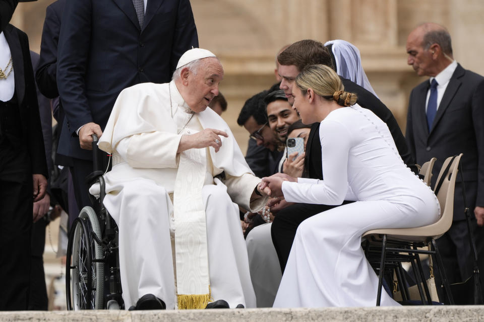 FILE - Pope Francis is greeted by a young married couple at the end of his weekly general audience in St. Peter's Square at The Vatican, on May 3, 2023. Pope Francis has formally approved allowing priests to bless same-sex couples, with a new document released Monday Dec. 18, 2023 explaining a radical change in Vatican policy by insisting that people seeking God’s love and mercy shouldn’t be subject to “an exhaustive moral analysis” to receive it. (AP Photo/Alessandra Tarantino, File)