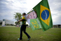 A woman holds a Brazilian flag and another with the image of Brazilian President Jair Bolsonaro, who is running for another term, after general election polls closed in Brasilia, Brazil, Sunday, Oct. 2, 2022. (AP Photo/Ton Molina)