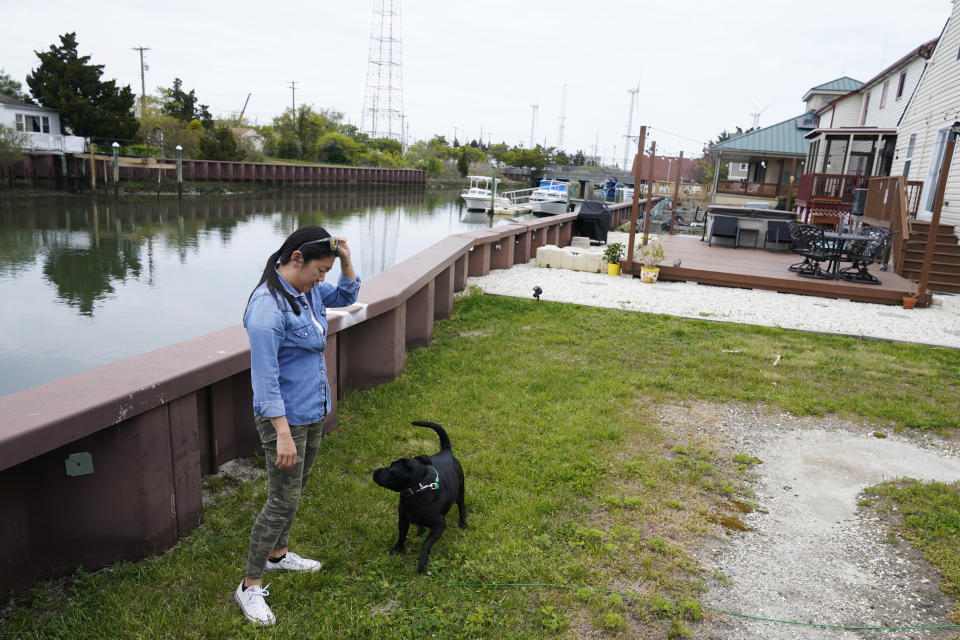 Abby Moul juega con su perro en el jardín de su casa, que da a un canal en Atlantic City (Nueva Jersey) el 4 de mayo del 2022. (AP Photo/Seth Wenig)