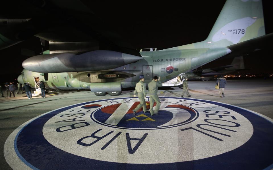 South Korean military crew members walk near two South Korean Air Force C-130 cargo planes carrying relief aid to Tacloban airport in central Philippines, at Seoul military airport in Seongnam