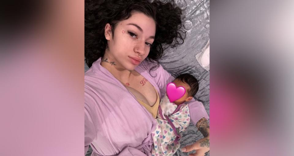 In an Instagram post, the “Bringing up Bhabie” star can be seen lying down with her child — whose face is concealed by a pink heart — while donning a pink robe and the newborn lay swaddled in a heart-printed blanket. @bhadbhabie / Instagram