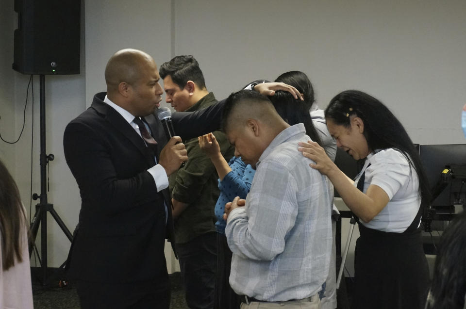 The Rev. Gustavo Castillo invokes God's grace on members of his congregation at the Iglesia Pentecostal Unida Latinoamericana in Columbia Heights, Minn., on Sunday, Sept. 24, 2023. Castillo ministers mostly to first- and second-generation migrants, but a sudden change in how the federal government processes some green cards means Castillo himself, and thousands of other foreign-born religious workers, might lose the ability to stay in the United States. (AP Photo/Giovanna Dell'Orto)