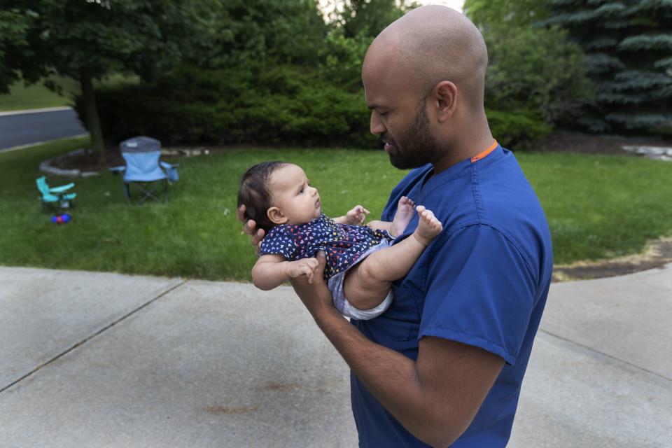 Jamie Jasti holds his 3-month-old daughter Nina after work at their home in Menomonee Falls.