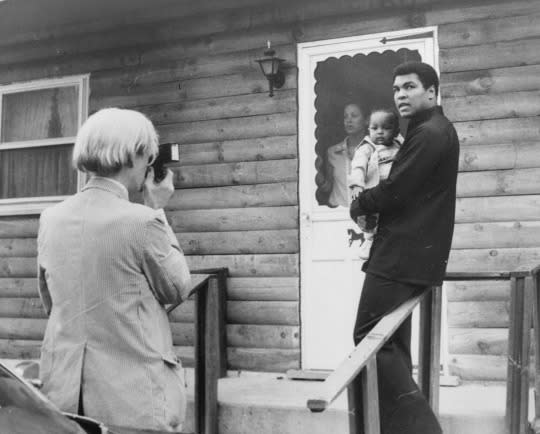 <p>Pop artist Andy Warhol, left, is shown photographing Muhammad Ali, his infant daughter, Hanna, and wife, Veronica, Thursday, August 18, 1977, at Ali’s training camp in Deer Lake, Pa. (AP Photo)</p>