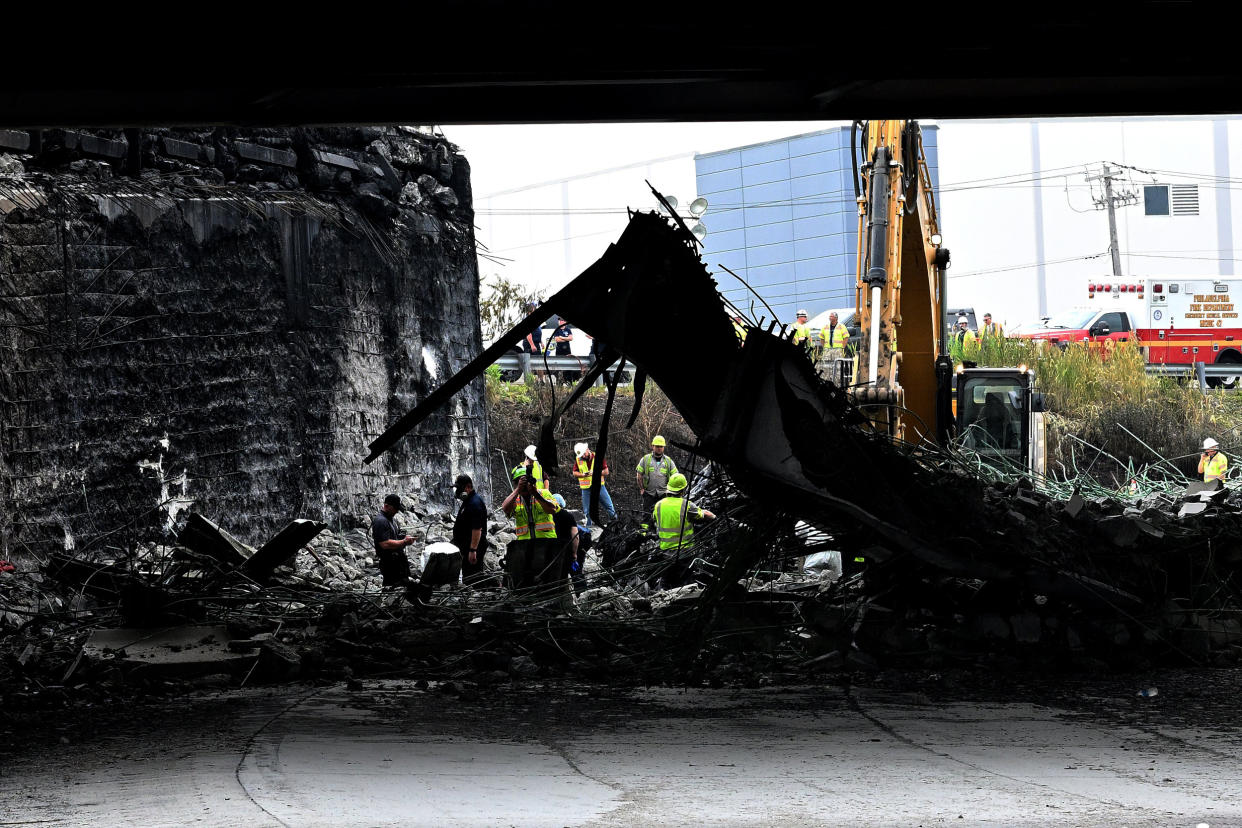 Workers inspect and clear debris from a section of the bridge that collapsed on Interstate 95 after an oil tanker explosion in Philadelphia (Mark Makela / Getty Images)