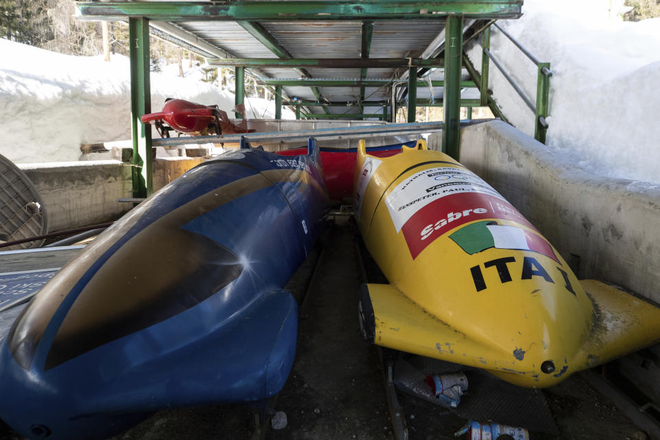 Bobsleds are parked next to the track in Cortina d'Ampezzo, Italy, Wednesday, Feb. 17, 2021. Bobsledding tradition in Cortina goes back nearly a century and locals are hoping that the Eugenio Monti track can be reopened for the 2026 Olympics in the Italian resort. (AP Photo/Gabriele Facciotti)