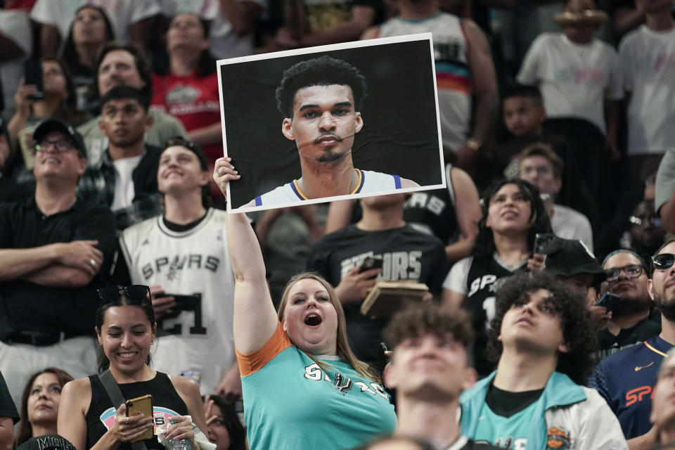 A fan holds a photo of Victor Wembanyama during an NBA basketball draft watch party at the AT&T Center in San Antonio, Thursday, June 22, 2023. The San Antonio Spurs selected Victor Wembanyama with the first pick. (AP Photo/Eric Gay)