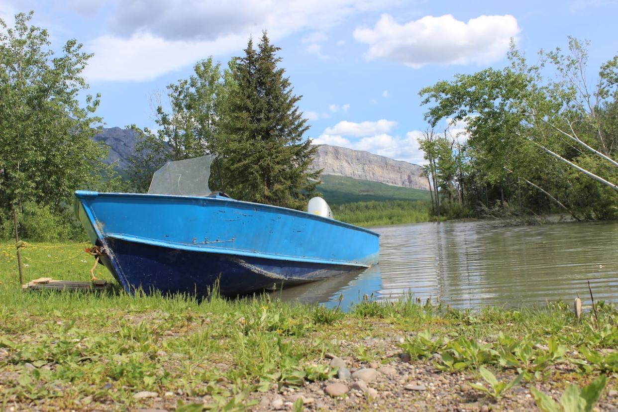 A boat sits in the high water of the South Nahanni River in Nahanni Butte, N.W.T., in June 2022.  (Liny Lamberink/CBC - image credit)