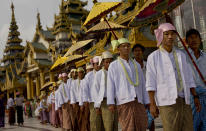 In this April 8, 2014 photo, a Buddhist men, would be temporary monks, dressed in Myanmar national attire, circumambulate the Shwedagon pagoda in hopes of winning a blessing from Buddha ahead of their ordination as Buddhist monks, Yangon, Myanmar. Though most of them only remain monks for a few days, ordination is seen as a right of passage in this predominantly Buddhist nation of 60 million. In addition to learning the basic tenants of their faith, it serves as a sort of spiritual credit for their parents, helping emancipate them from a viscous cycle of rebirth and death. (AP Photo/Gemunu Amarasinghe)