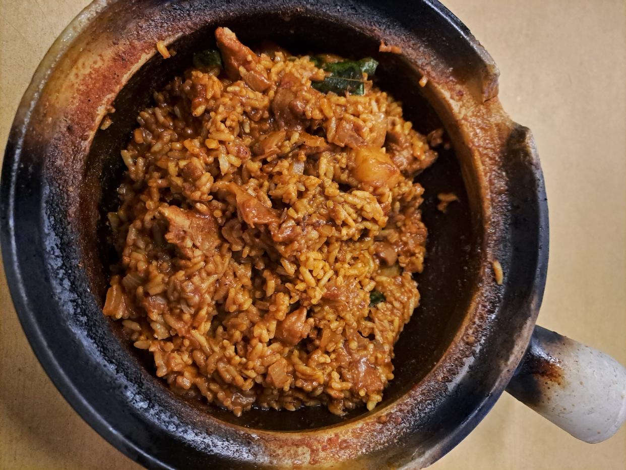 A picture of cooked brown claypot rice with lizard meat in a claypot.