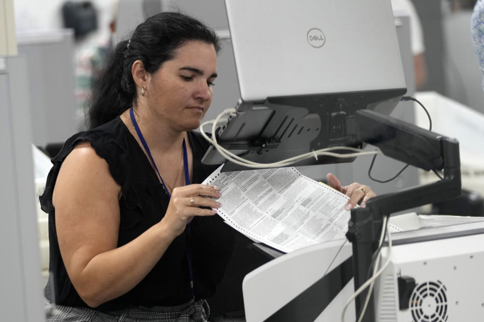 A worker organizes vote-by-mail ballots for scanning during the midterm election at the Miami-Dade County Elections Department, Tuesday, Nov. 8, 2022, in Miami. On Friday, Nov. 18, The Associated Press reported on stories circulating online incorrectly claiming Florida’s ability to report election results quickly during the 2022 midterms means states that have taken longer, such as Arizona and Nevada, are engaged in fraud. (AP Photo/Lynne Sladky)