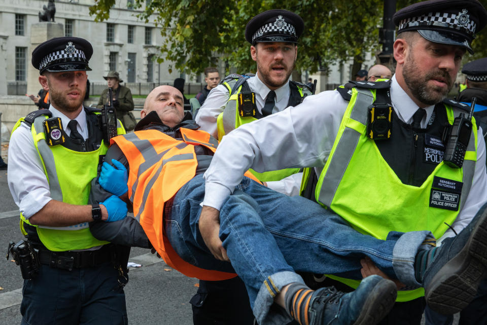 Metropolitan Police officers arrest a climate activist from Just Stop Oil who had blocked the road in front of New Scotland Yard to call on the UK government to cease issuing oil and gas licences.on 14 October 2022 in London, United Kingdom. Some activists also spray painted the rotating New Scotland Yard sign outside the building with yellow paint. The Metropolitan Police made 24 arrests on suspicion of wilful obstruction of the highway and/or conspiracy to commit criminal damage. (photo by Mark Kerrison/In Pictures via Getty Images)