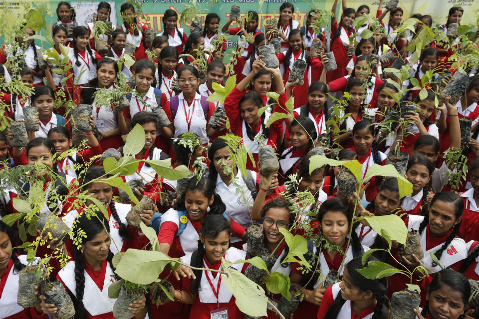 Indian school children hold saplings distributed by the government in Prayagraj, India , Friday, Aug. 9, 2019. More than a million Indians planted saplings as part of a government campaign to tackle climate change and improve environment in the country’s most populated state. (AP Photo/Rajesh Kumar Singh)