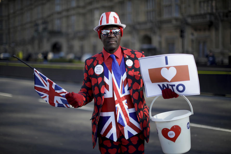 Leave the European Union supporter Joseph Afrane, aged 55 from London and originally from Ghana, poses for photographs outside the Houses of Parliament in London, Thursday, Feb. 14, 2019. Joseph believes leaving the European Union with no-deal would be the best way forward and believes Britain has been neglecting its relationship with the Commonwealth since joining the EU. The colorful debate over Britain's Brexit split with the European Union has spilled over from Parliament to the grounds outside, traditionally a marketplace for ideas, protests and rallies.(AP Photo/Matt Dunham)