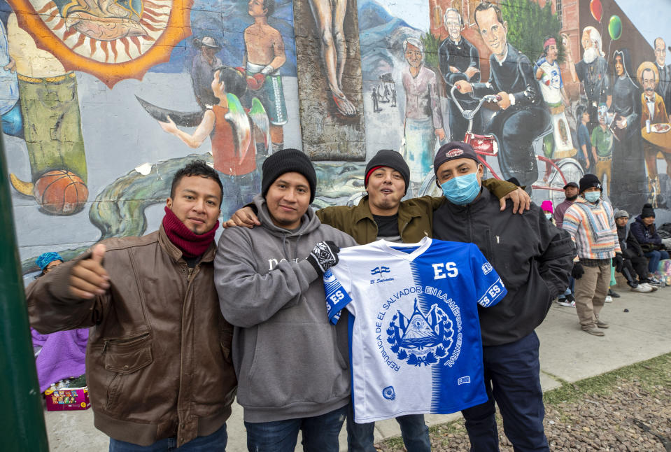 Migrants from El Salvador pose for a photo while waiting for help on a street in downtown El Paso, Texas, Sunday, Dec. 18, 2022. Texas border cities were preparing Sunday for a surge of as many as 5,000 new migrants a day across the U.S.-Mexico border as pandemic-era immigration restrictions expire this week, setting in motion plans for providing emergency housing, food and other essentials. (AP Photo/Andres Leighton)
