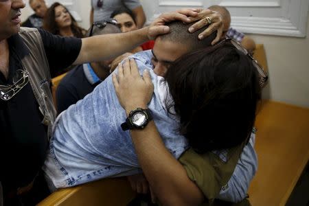 An Israeli soldier, charged with manslaughter by the Israeli military after he shot a wounded Palestinian assailant as he lay on the ground in Hebron on March 24, is hugged by his mother during a hearing at a military court in Jaffa near Tel Aviv, Israel April 18, 2016. REUTERS/Baz Ratner