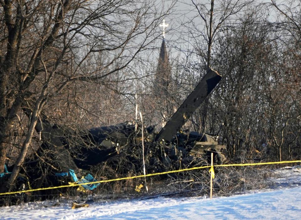 In this Thursday, Dec. 5, 2019, photo the steeple of Holy Cross Catholic Church in Kimball, Minn., rises in the distance over the deadly crash site of a Minnesota National Guard Blackhawk helicopter. (Brian Peterson/Star Tribune via AP)