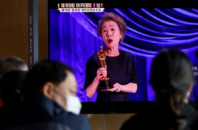 People watch a TV broadcasting a news report on Youn Yuh-jung winning the best supporting actress Oscar, in Seoul